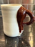 Profile view of mug showing white body and brown horse tail handle