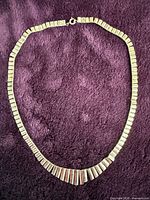 Full view of graduated sterling silver necklace on purple background