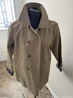Front view of khaki double-breasted trench coat on mannequin