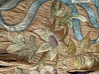 Close-up of silk embroidery showing blue ribbon and floral motif