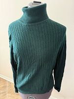 Front view of hunter green cable knit turtleneck sweater on mannequin