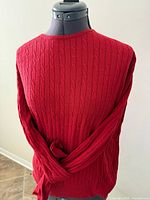 Rear view of red cable-knit sweater on mannequin