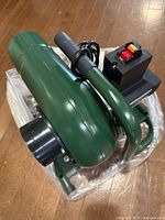 angled top view of green dust collector showing handle, motor housing, power switch, cord and accessories bag
