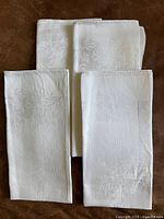 Four folded white double-damask linen napkins laid out