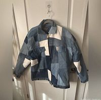Front view of Carhartt upcycled patchwork denim jacket on hanger