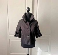 Front view of Samuel Dong black jacket on mannequin showing button closure, collar, sleeve detail