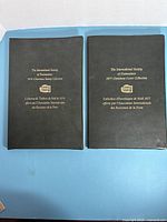 Front covers of both black binders showing gold text and emblem