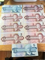 Overview of all nine Canadian paper notes laid out on table