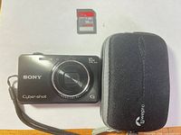 Front view of Sony DSC-WX150 camera, SanDisk 16 GB SD card, Lowepro case