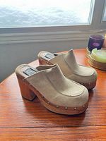 Side view of tan suede clogs on wood platform heels
