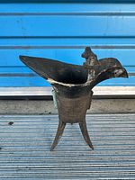 Side view showing spout, finial posts, tail and tripod legs