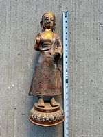 Full view of standing Buddha statue beside measuring tape showing height ~12 inches