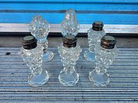 Front view of six cut glass shakers