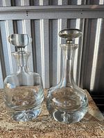 Front view of both clear glass decanters with stoppers
