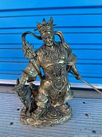 Front view of brass warrior statue with spear and dog