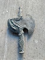 Front view of carved stone axe showing dragon relief and blade details