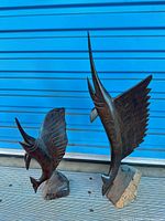 Two carved hardwood sailfish sculptures on deck against blue background