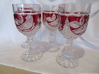 Front view of four ruby red crystal goblets showing bird cut pattern