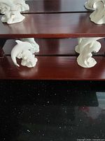 Front view of two-tier wood shelf with two porcelain dolphin figures on each tier