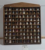 Full view of wooden display case filled with thimbles