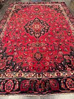 Full view of red Mashhad rug showing overall pattern and border