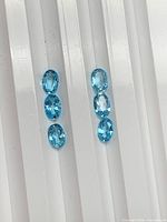 Six blue oval gemstones aligned in two columns