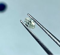 Diamond held in tweezers showing marquise shape and faceting