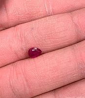 Pear-shaped ruby on fingertip showing size and color