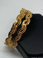 Two gold-tone wavy bangles side view