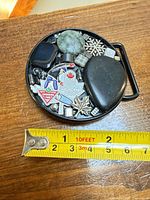 Front view showing entire decorated buckle with tape for scale