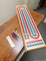 Full view of wooden Bicycle three-track cribbage board, pegs and metal cover