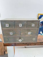 Front view of entire wooden chest showing six drawers and metal knobs