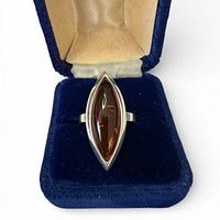 Ring in presentation box, top view shows amber stone and silver setting