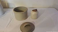Crock, jar with cork, and lid on table