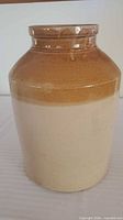 Front view of brown and cream glazed stoneware crock jar