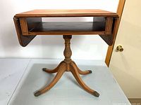 Side table with leaves down showing shelf, pedestal, legs, brass feet
