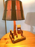 Full view of carved wood table lamp with shade, base scene visible