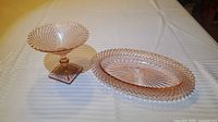 Pink Depression glass footed bowl and oval tray on table