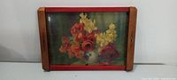 Front view of tray showing wood frame, red rails, glass inset with floral print