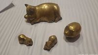 All four brass pig figurines grouped together