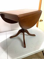 Table with leaves down showing pedestal base and one leaf folded