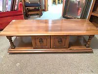Full view of maple coffee table showing top, legs, shelf, and drawer fronts