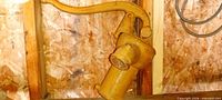 Overall view of yellow cast-iron pump mounted on wood wall