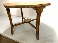 Full view of solid wood table showing legs, stretcher and carved apron