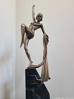 Full view of bronze-tone figurine on black base