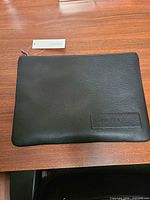 Front view of black Calvin Klein faux leather pouch with tag attached