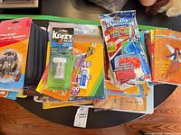Group on table showing shoelaces, Krazy Glue, workbooks, coloured pencils, water balloons and stack of children’s books