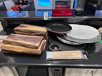 Lot overview showing wood boards, metal platters, glass plates, pizza pan, bamboo skewers
