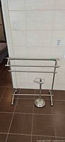 Metal 3-bar towel rack and toilet paper holder on tile floor