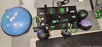 Overall view of BodyBoss platform with bands, connector bar, bag, BOSU, medicine balls, kettlebell and ab wheel